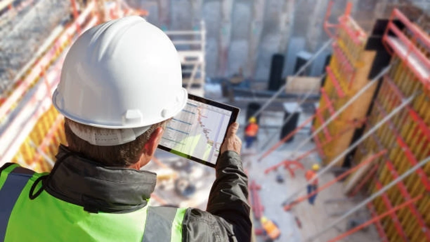 Two project leaders walk past repeated structural bays at different stages of construction.
