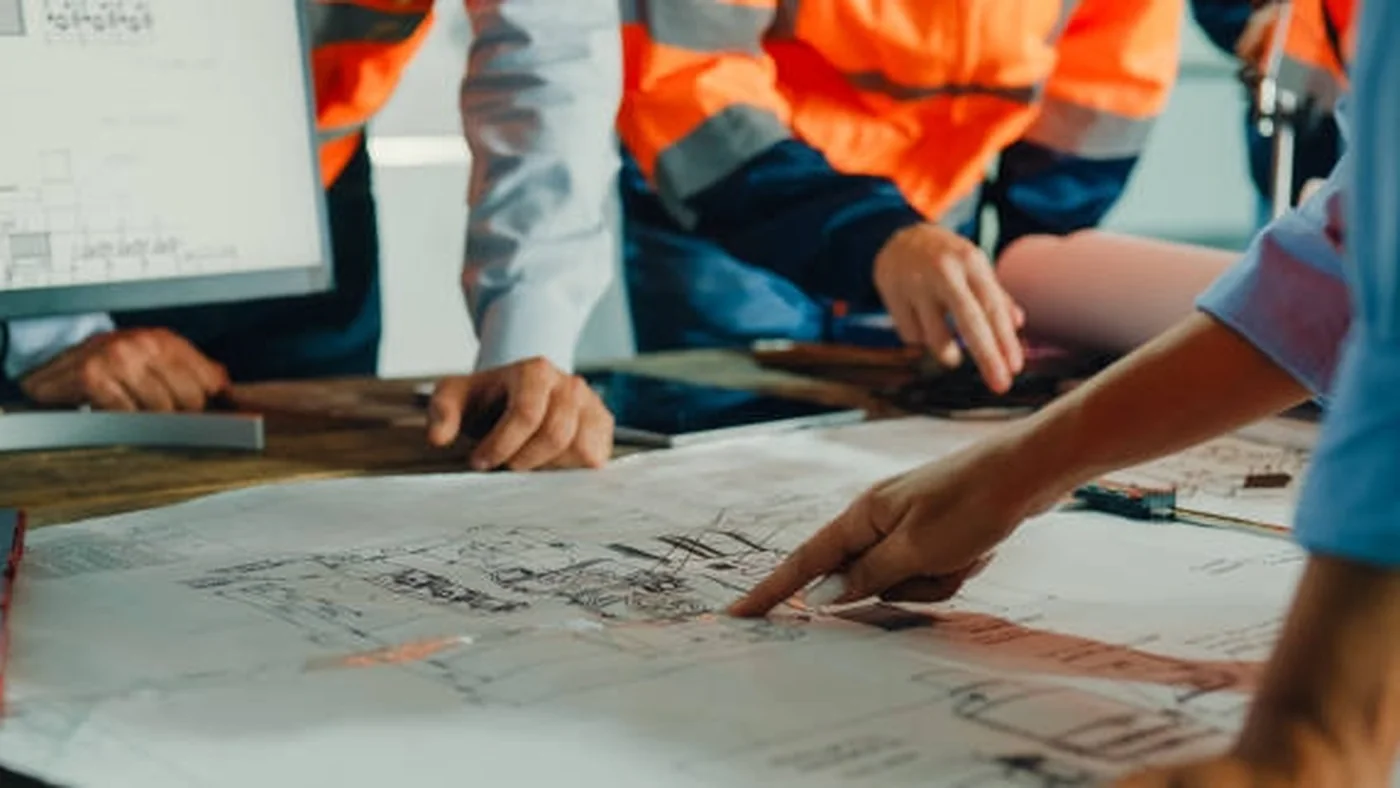 Three project leaders review an active concrete and steel building site from an elevated terrace.